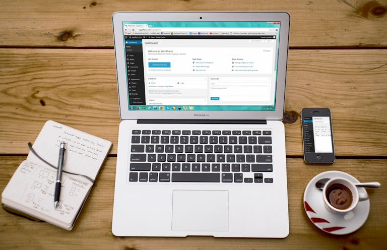 Une scène de bureau à domicile confortable avec un ordinateur portable, un ordinateur portable, un smartphone et du café, parfaite pour la productivité. La création d'un site WordpPress est en cours