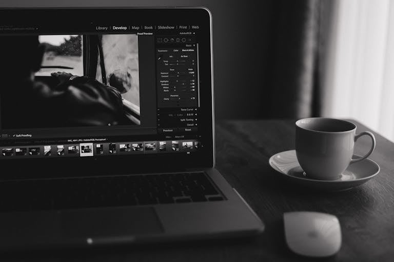 Photo minimaliste en noir et blanc d'un ordinateur portable avec du café. Idéale pour un bureau à domicile. Sous-traitance d'un développement web en marque blanche